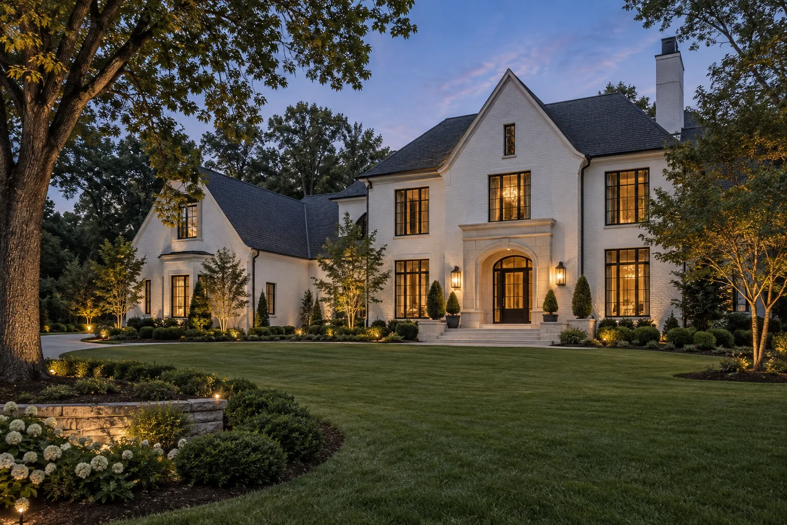White brick Southern estate with limestone entry and soft landscape lighting